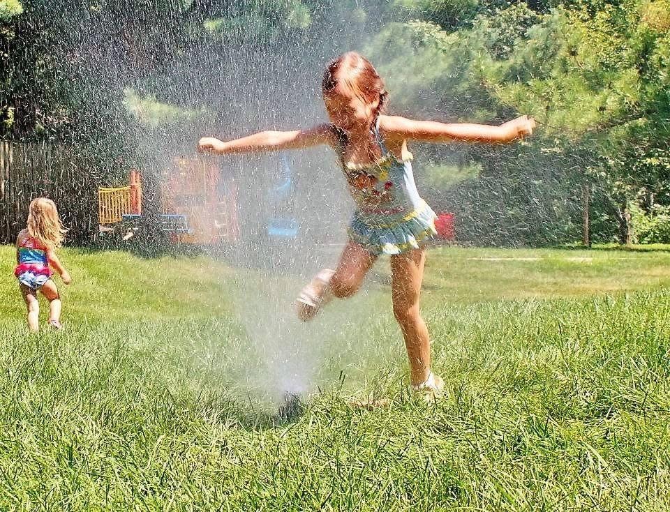 Kids playing in the sprinkler at Kiddie Care preschool